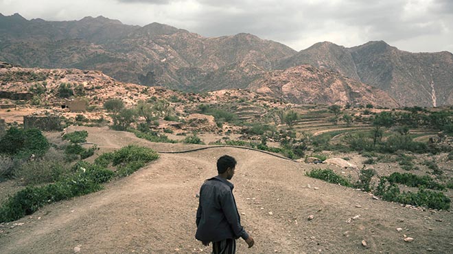 محمد فليت أحمد يسير بين تلال قريته ، موليس ، في منطقة المغاربة باليمن